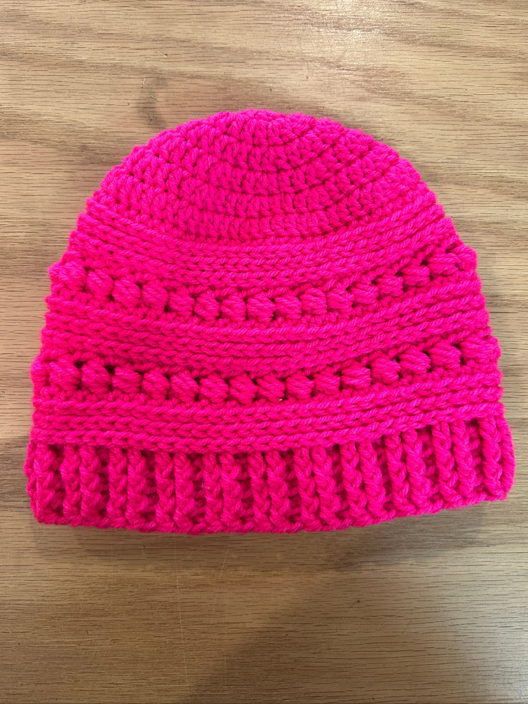 Pink knitted beanie on a wooden surface